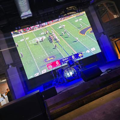 View of the projector inside a venue, displaying a live football game.