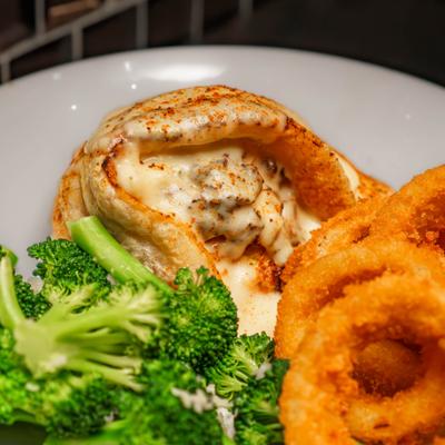 Stuffed Pollock served with onion rings and broccoli, close-up.