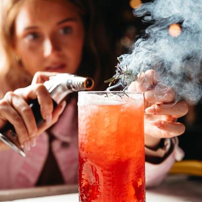A person preparing a smoking cocktail.