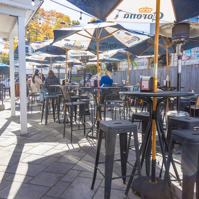 Outdoor seating area on the patio with bar tables and chairs under parasols.