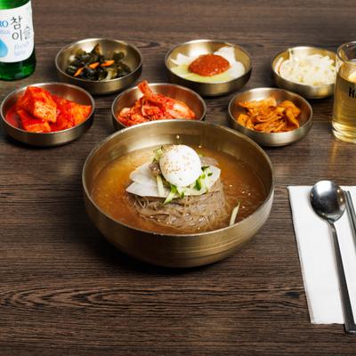 Korean cold buckwheat noodles in a chilled broth served with various side dishes.