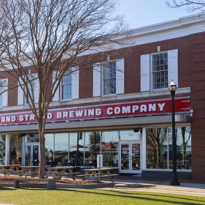 Grand Strand Brewing Company storefront with sunlit outdoor seating.