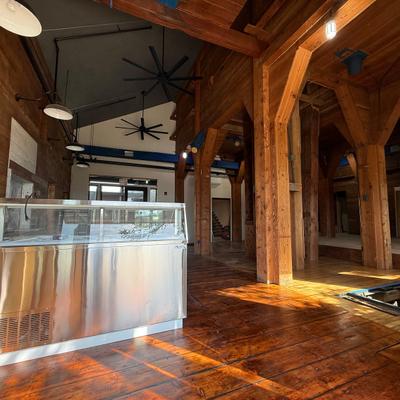 Interior featuring timber-frame beams, hardwood flooring and a food service counter.