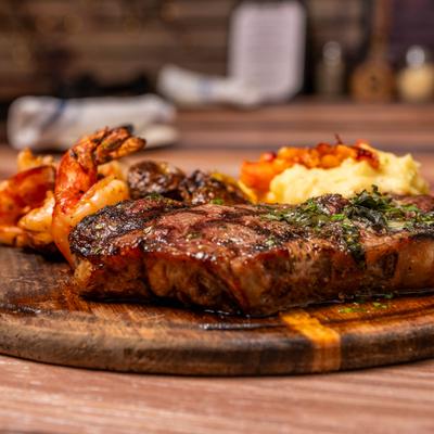 Grilled steak with shrimp and mashed potatoes on a wooden board.