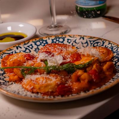 Ravioli topped with tomato sauce, cheese, and fresh herbs.