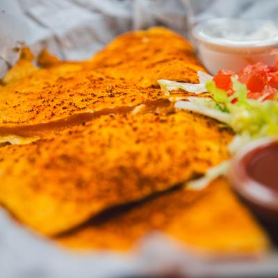 Quesdilla served with fresh vegetables and sauces, close-up.