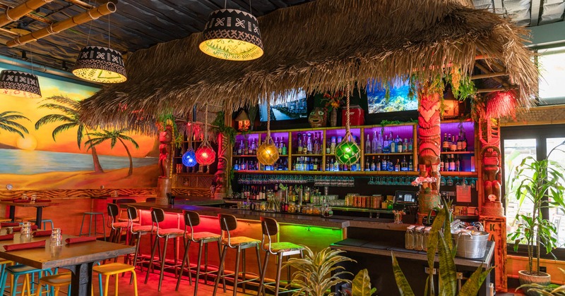 Interior, bar area, wooden top bar with stools, large drink shelf, beach mural on the wall