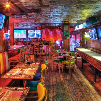Interior with colorful chairs, games on TV screens, eclectic decorations, and warm lighting