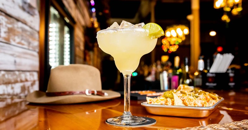 A cozy place with cocktail and western hat on table in front.