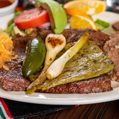 Grilled steak topped with roasted peppers, spring onions, and cactus with rice and beans.