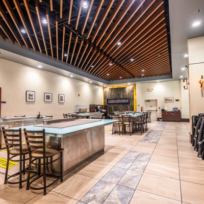 Modern dining area, empty tables, ceiling with wooden slats, blue accent wall and industrial lights.