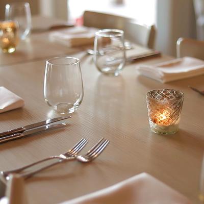 Dining table, with glasses, napkins, utensils, and candles
