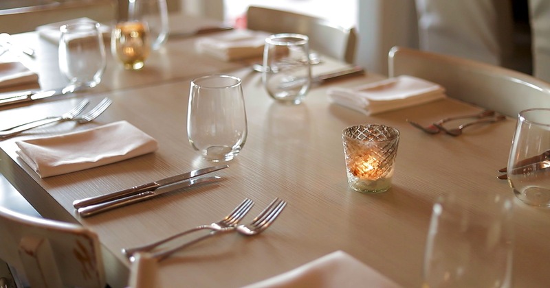 Dining table, with glasses, napkins, utensils, and candles