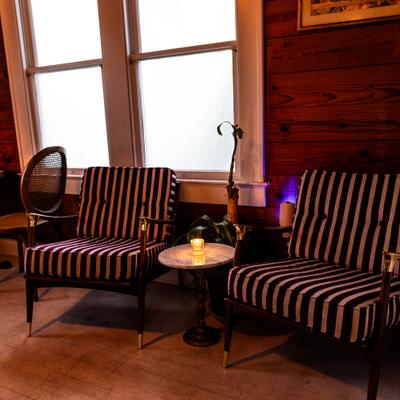 Two striped lounge chairs beside a small round candlelit table.