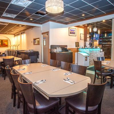 Interior with large central dining table and bar area in the background.