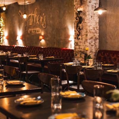 Dining area with booth and table seating, overhead lights and sign on the wall.