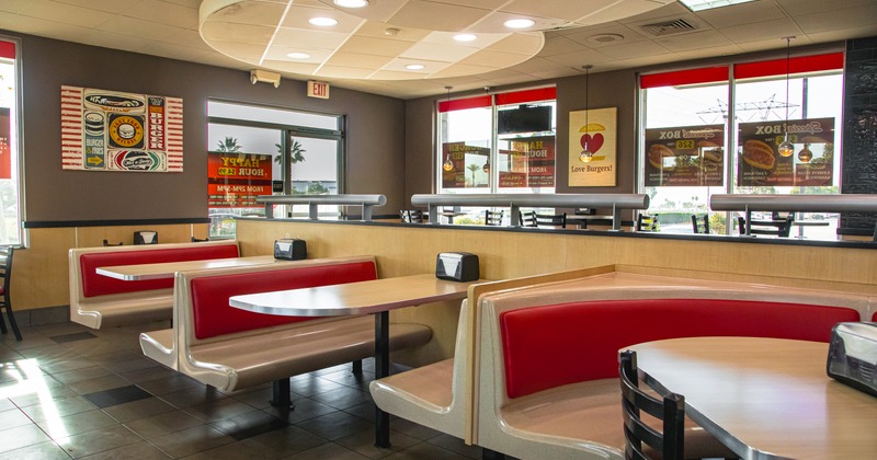 Casual dining interior - red cushioned booths, wooden tables, vintage posters and large windows