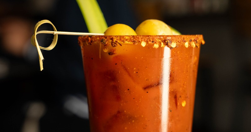 Bloody Mary cocktail garnished with a chili rim, olives and celery