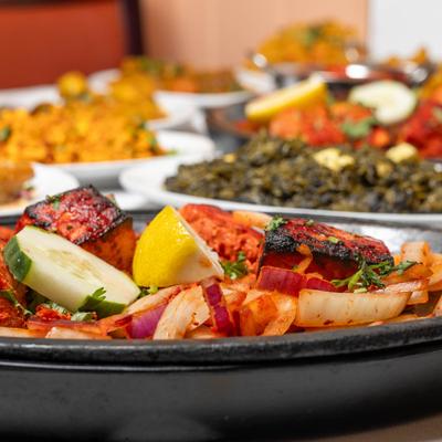 Close up of Salmon tikka plate, with various food dishes in the background.