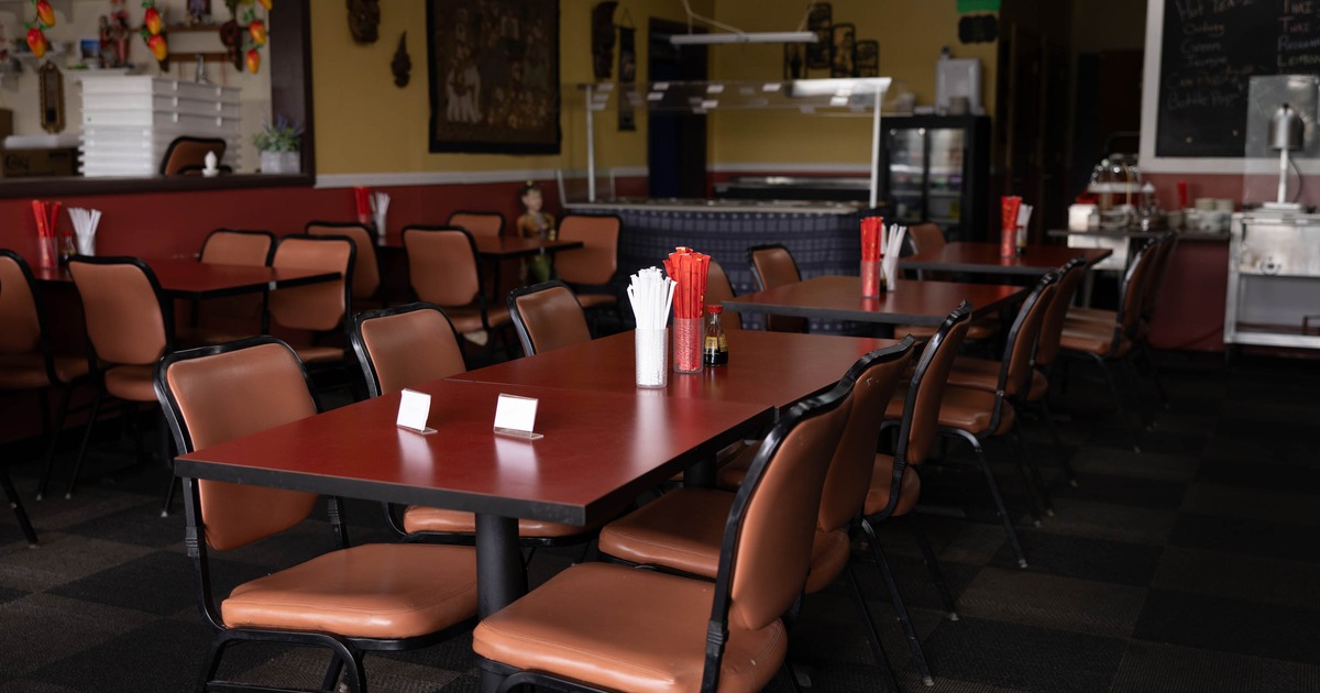 Interior of a casual dining restaurant with red tables, brown chairs, and a checkerboard floor