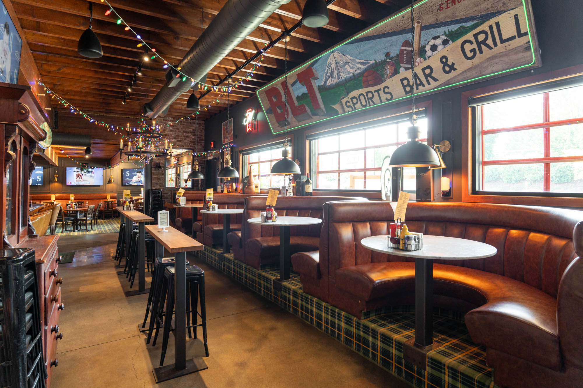 Interior, sports bar, cozy leather booths, wooden tables and pendant lighting