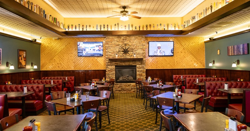 Spacious dining area with a fireplace, tables, chairs, and upholstered booths along the walls