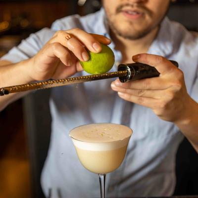 Grating lime over a cocktail.