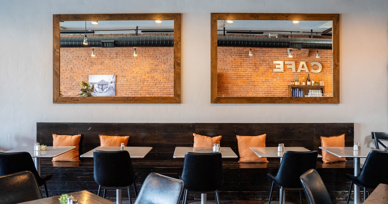 Interior, black furniture, orange cushions and large mirrors reflecting a brick wall