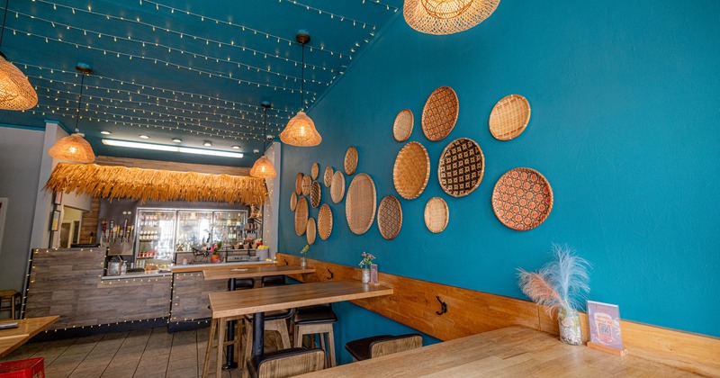 Interior, high seating wooden top tables with stools, checkout in the back