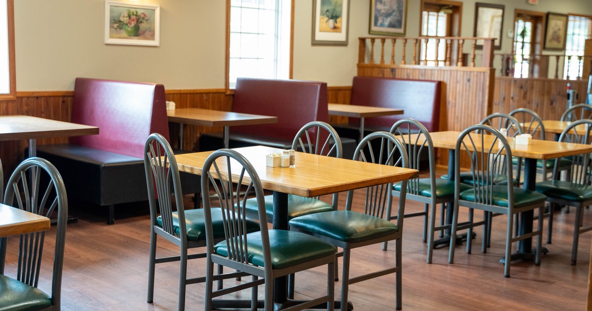 Interior - wooden floors, wooden tables, black metal chairs, burgundy booth seating along the walls.