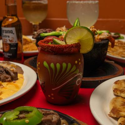 Cantarito cocktail in a traditional clay mug with a Tajin rim and lime garnish.
