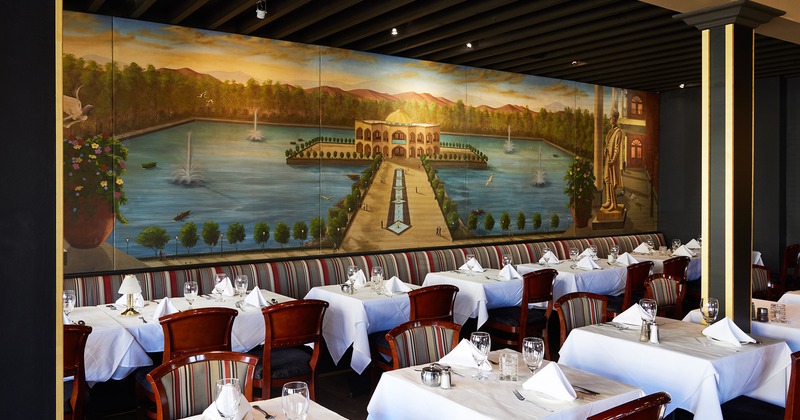 Nicely done interior dining area with set tables and a large mural on the wall