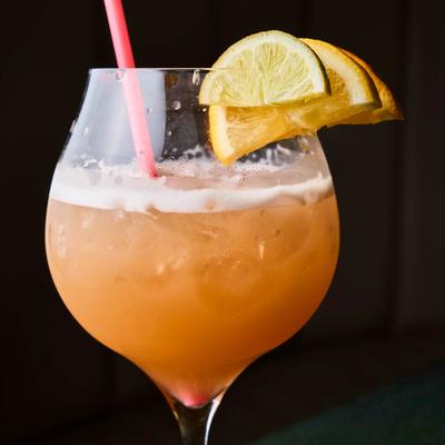 Citrus cocktail garnished with lemon and lime wedges.