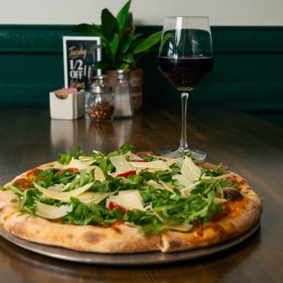 Pizza topped with arugula, cherry tomatoes, and Parmesan, paired with red wine.