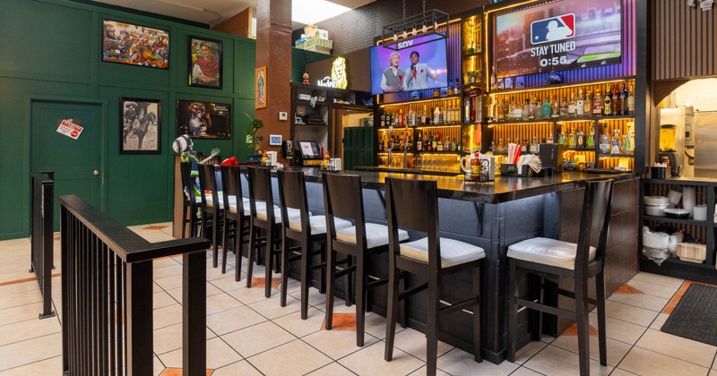 Interior, bar area, wooden top bar with bar stools, large drink shelves, TVs on the wall
