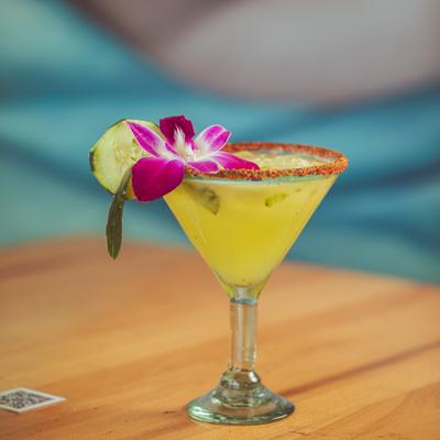 Yellow cocktail drink with purple flower garnish