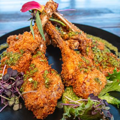 Breaded lamb chops served with greens and garnishes.