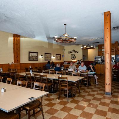 Diner with wooden tables, chairs, and rustic decor, Patrons seated at tables.