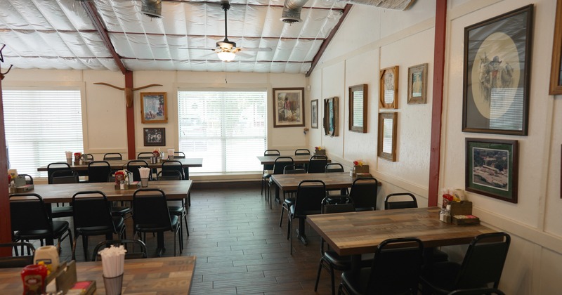 Interior of a cozy, rustic-style restaurant with wooden tables and simple black chairs