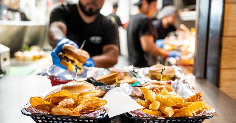 A busy kitchen scene showing chefs preparing burgers and fries