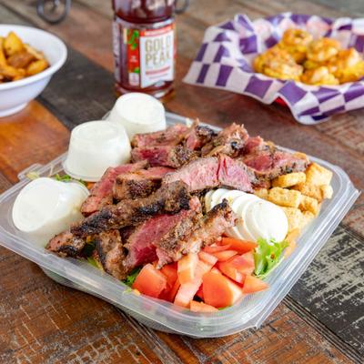 Ribeye Steak Salad served on the table with other dishes and a drink.
