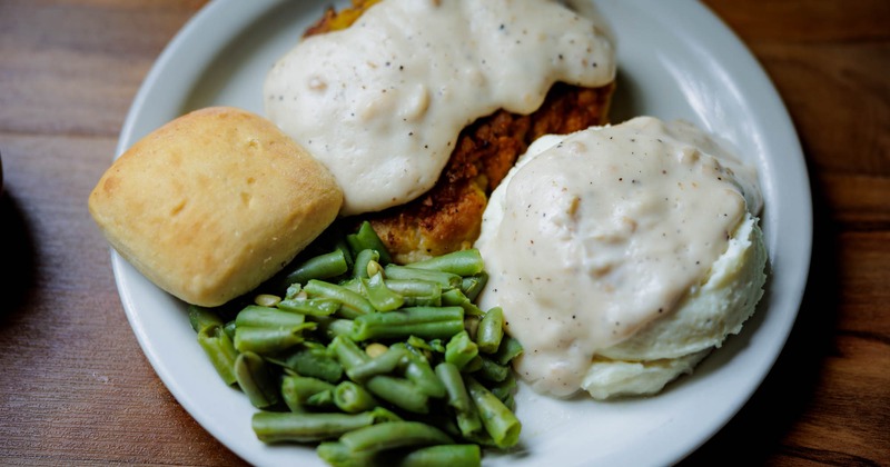 Chicken Fried Steak with sides of mashed potato, gravy, green beans and bread