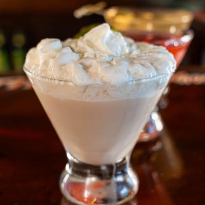 Creamy cocktail topped with whipped cream in a stemless martini glass