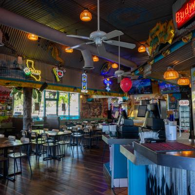Interior with a counter area, table seating, neon signage and overhead lightning.