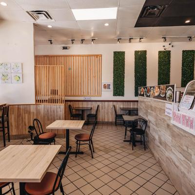 Interior with wooden tables, chairs, and decorative greenery on the wall.