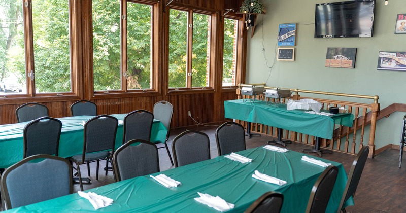 Dining room with teal tablecloths, large windows, and a buffet table