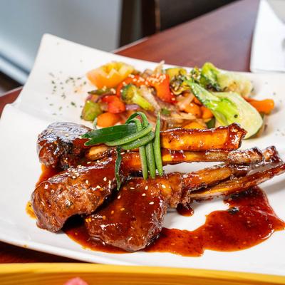 Cooked lamb chops served with a side of stir-fried vegetables.