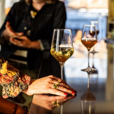 Hand beside a wine glass on a shiny bar counter.