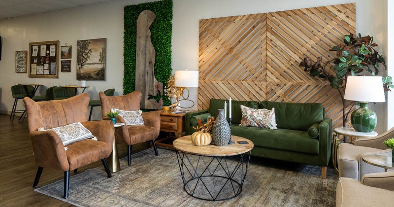 Cozy interior with a green sofa, brown chairs, wooden coffee table and decorative elements