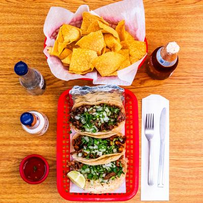 Tacos asada with chips and drinks.